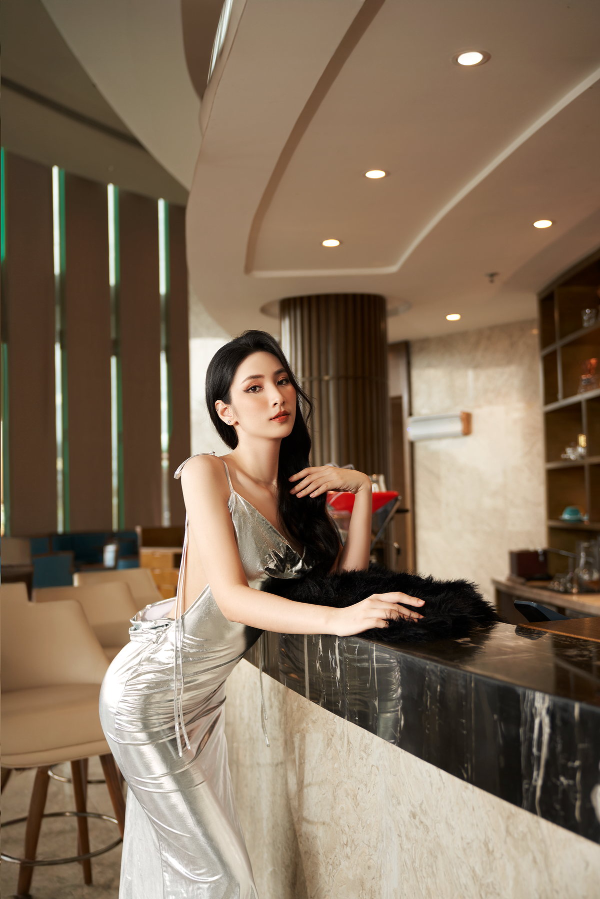 Một vị khách trong trang phục ánh bạc đứng bên quầy bar khách sạn