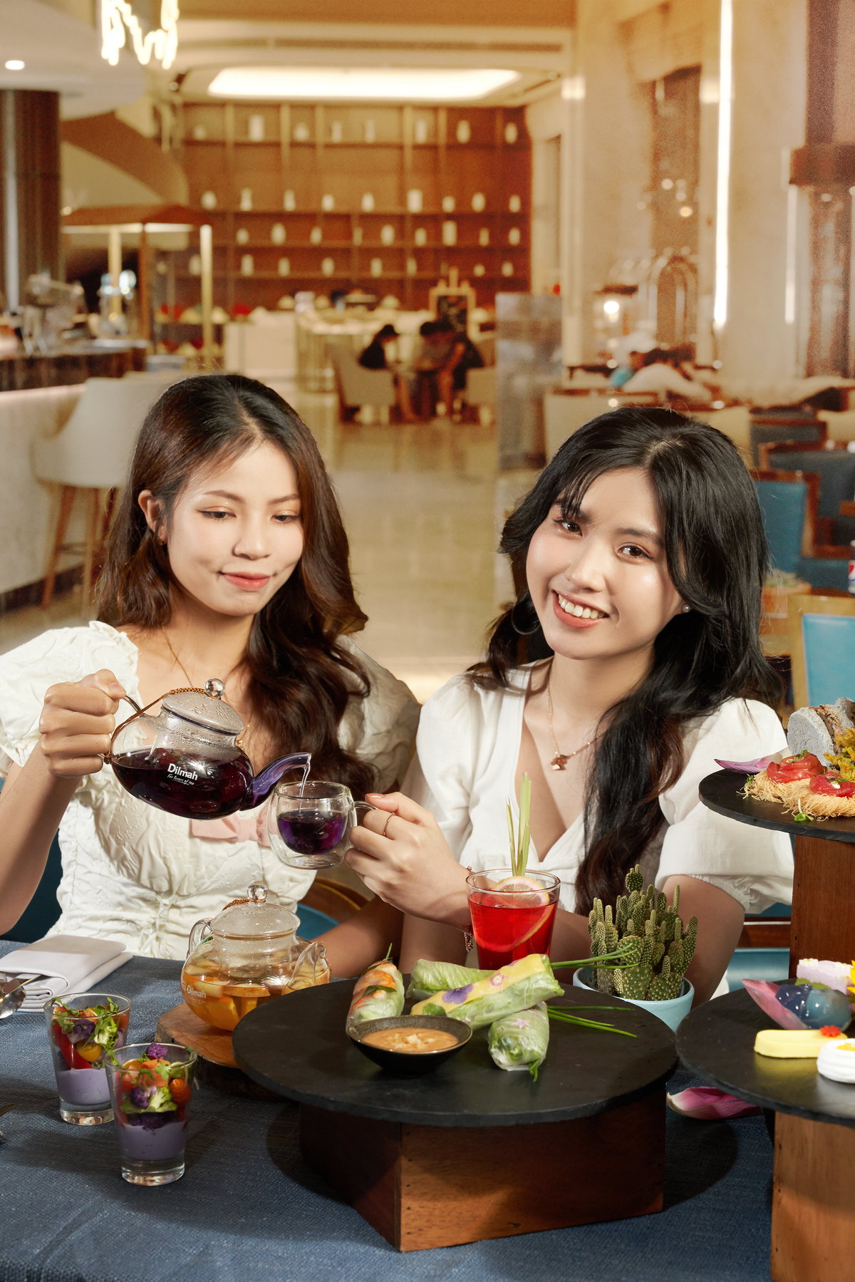Một vị khách rót trà tím cho bạn bên bàn Floral High Tea
