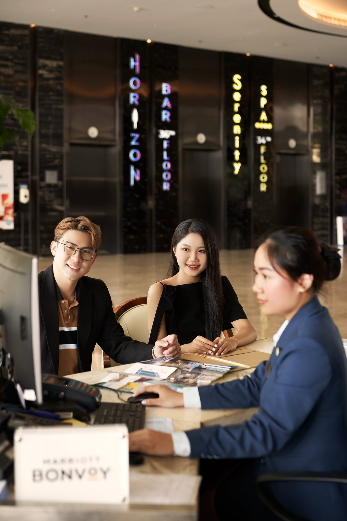 Nhân viên lễ tân hỗ trợ hai vị khách tại quầy Four Points Danang