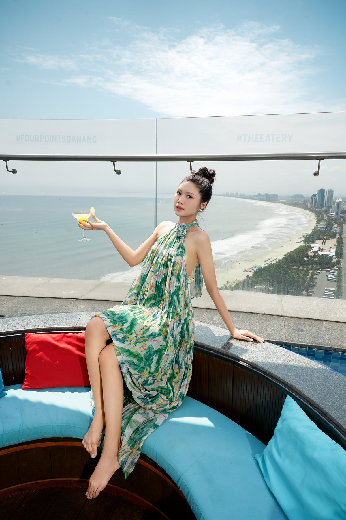 Một vị khách ngồi bên hồ bơi tầng thượng với ly đồ uống