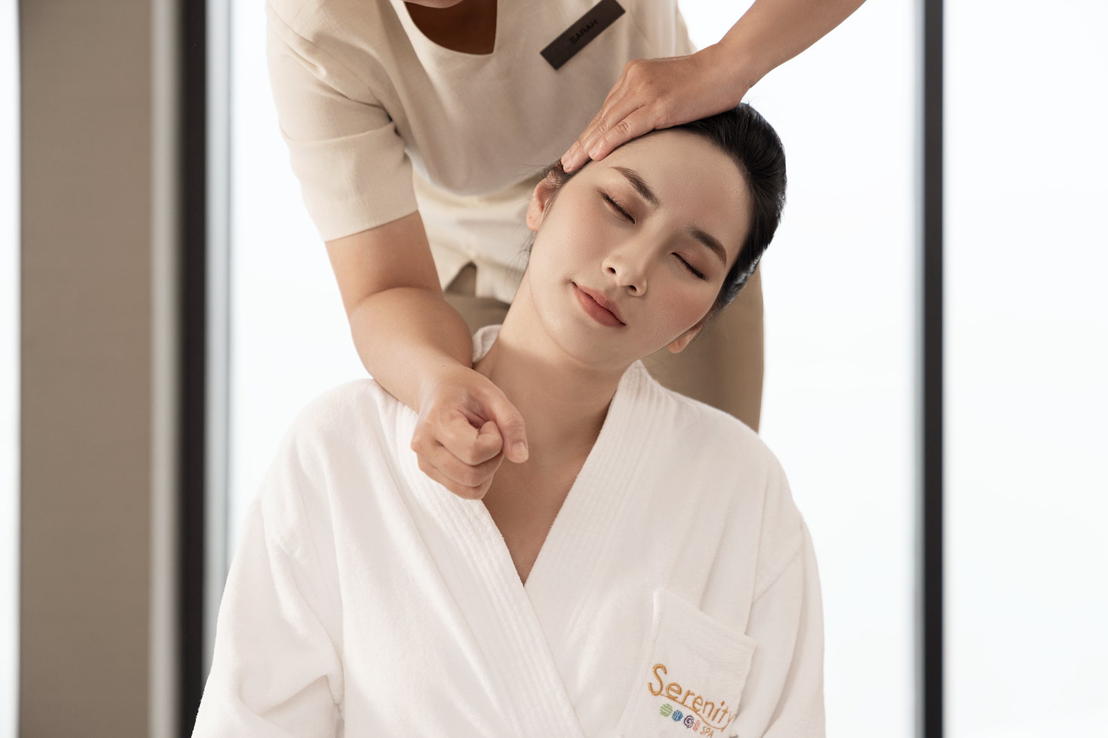Trị liệu viên massage đầu và cổ cho một vị khách tại Serenity Spa