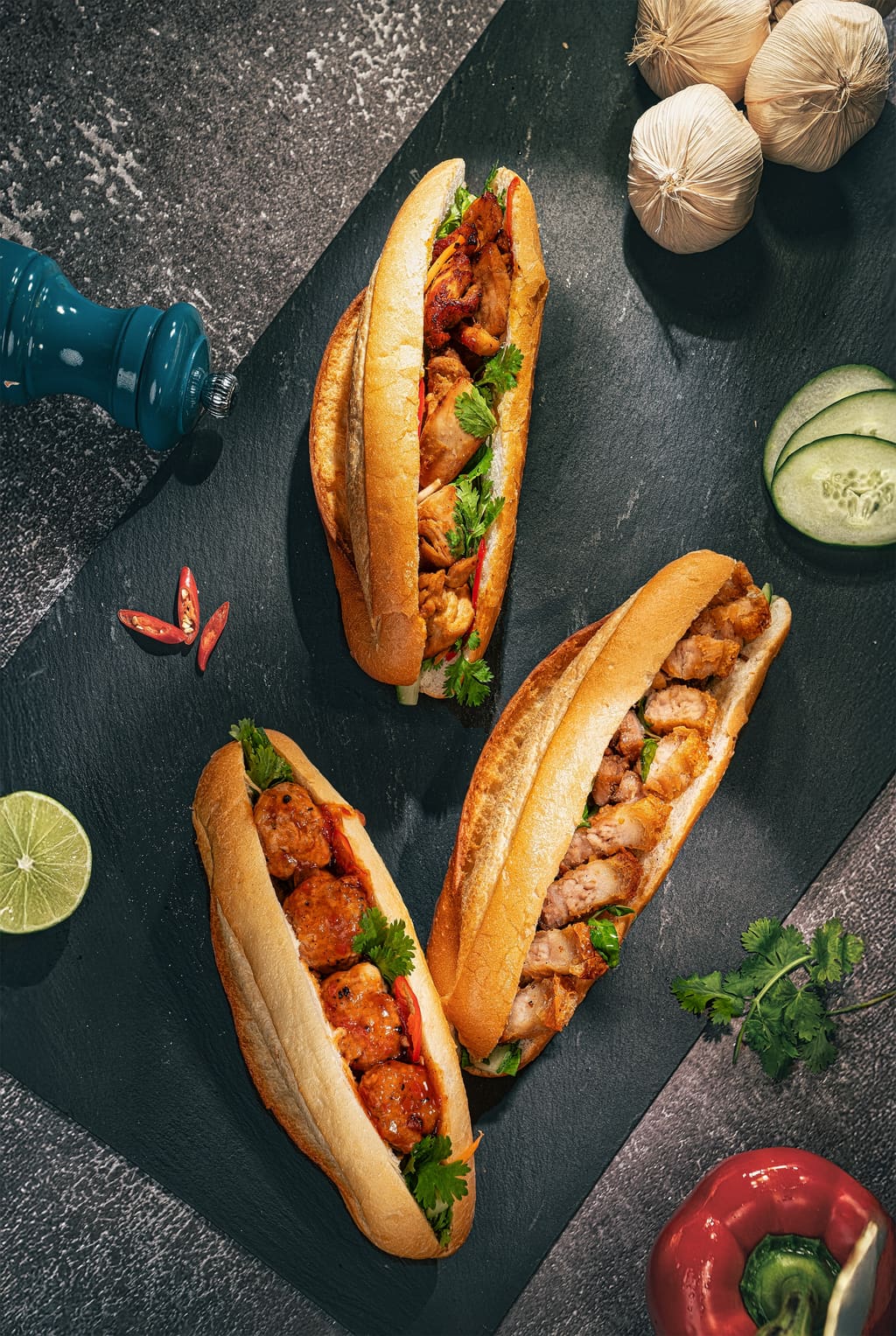 Hai phần bánh mì trình bày trên nền tối cùng rau và nước chấm