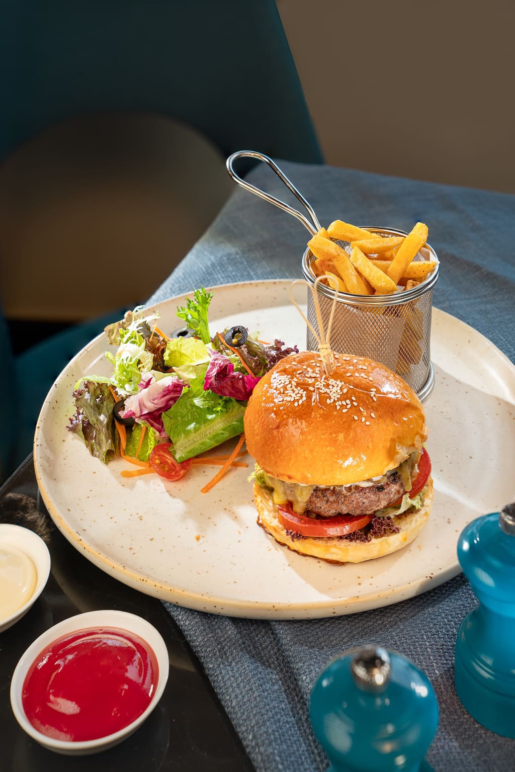Hamburger, khoai tây và salad trên bàn ăn