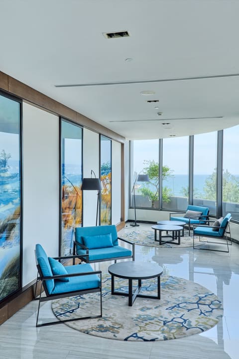 Khu đón khách Hilton với ghế xanh và cửa kính nhìn ra biển