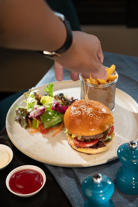 Bàn tay hoàn thiện món burger trong buổi chụp ẩm thực