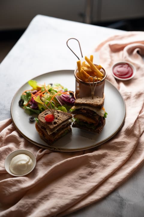 Club sandwich, khoai tây và salad trên bàn ăn