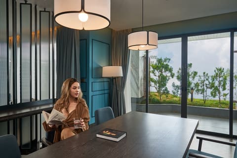 Khách nữ đọc sách tại bàn trong không gian sinh hoạt chung của khách sạn