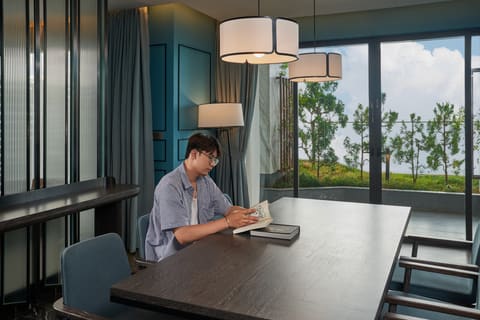 Khách nam ngồi đọc và làm việc tại bàn trong khách sạn