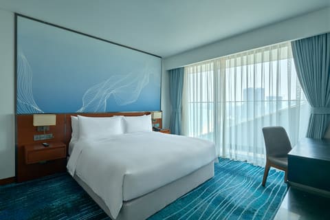 Phòng giường lớn với tường xanh và cửa sổ tại Hilton Garden Inn Đà Nẵng