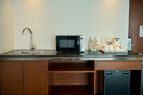 Khu bếp nhỏ trong suite với bồn rửa, lò vi sóng và minibar