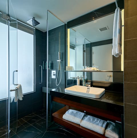 Phòng tắm khách sạn với lavabo, gương và buồng tắm đứng