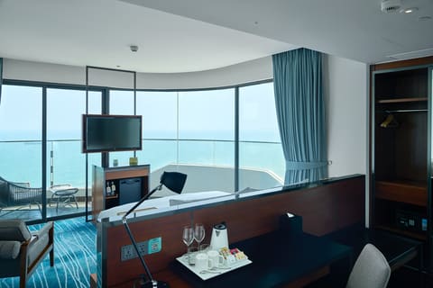 Bàn làm việc trong suite nhìn qua giường và ban công hướng biển