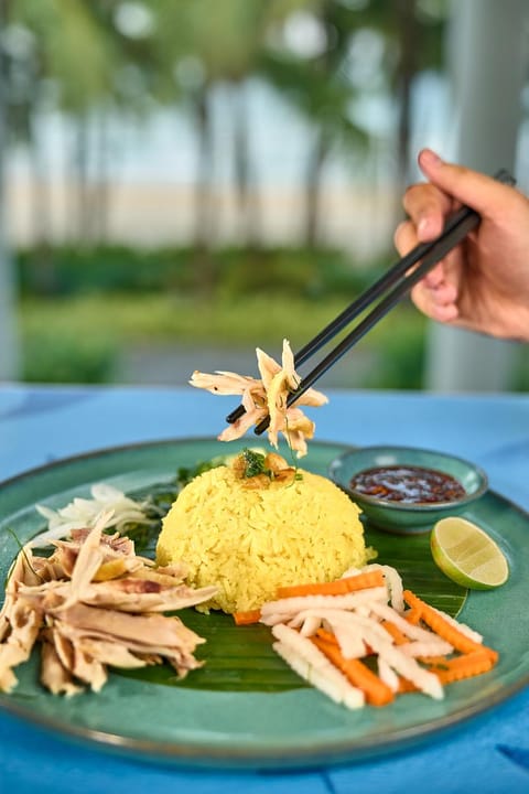 Đũa gắp một phần cơm gà trên nền xanh