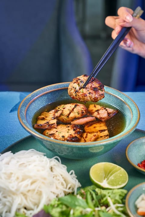 Đũa gắp thịt nướng phía trên tô bún