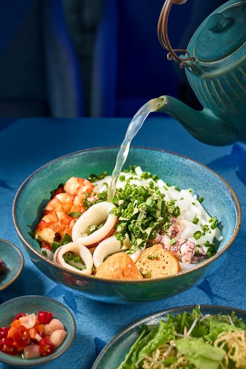 Nước dùng được rót vào tô bánh canh hải sản