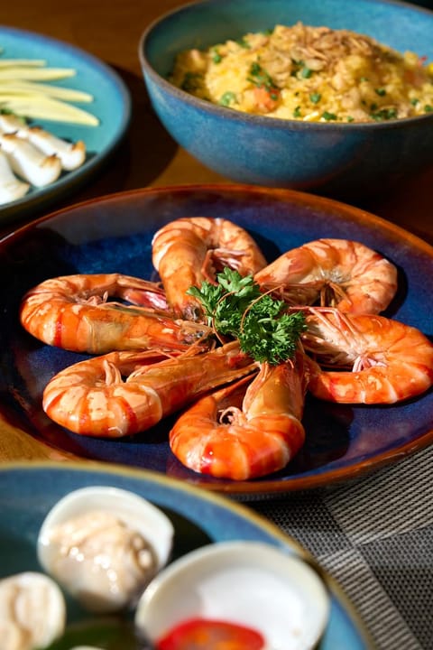 Đĩa tôm giữa các món dùng chung trên bàn gỗ