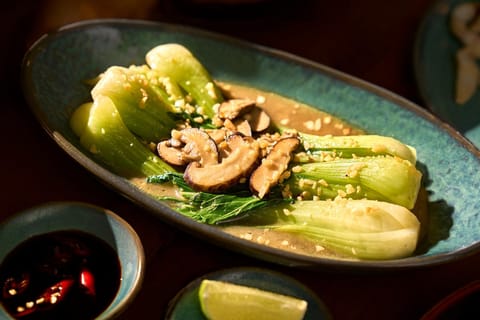 Món cải thìa và nấm trên mặt bàn gỗ ấm